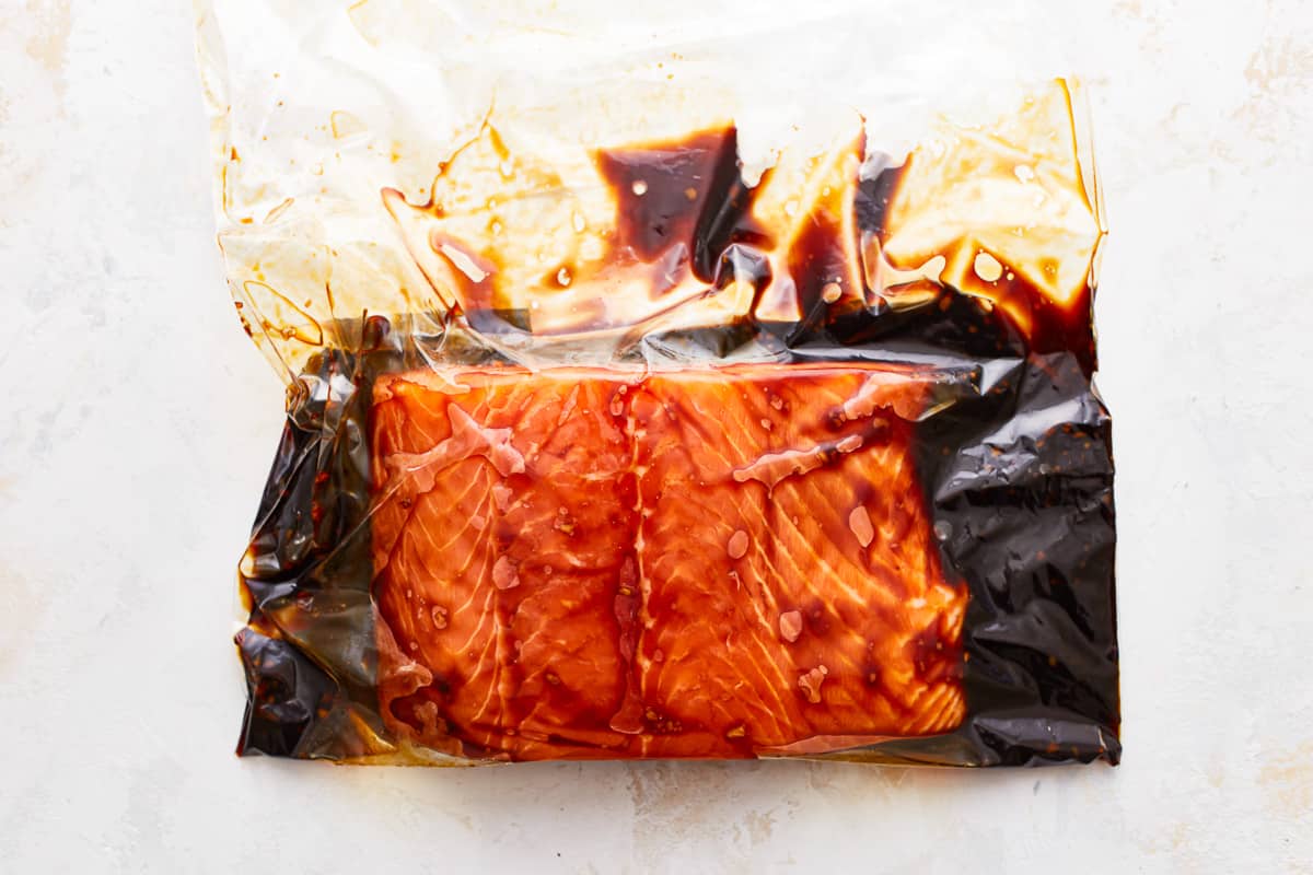A piece of salmon in a plastic bag with sauce on it.