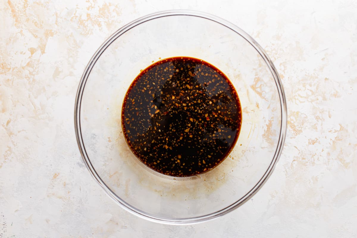 A bowl filled with a sauce on a white surface.