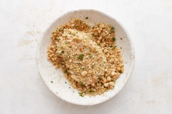 A white bowl filled with granola and herbs.