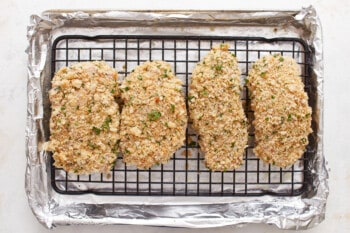 Four fried chicken breasts on a cooling rack.