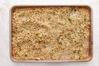 A baking sheet with a mixture of breadcrumbs and herbs.