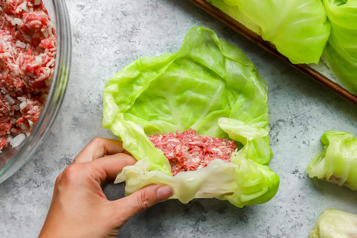 A person filling cabbage leaves with meat.