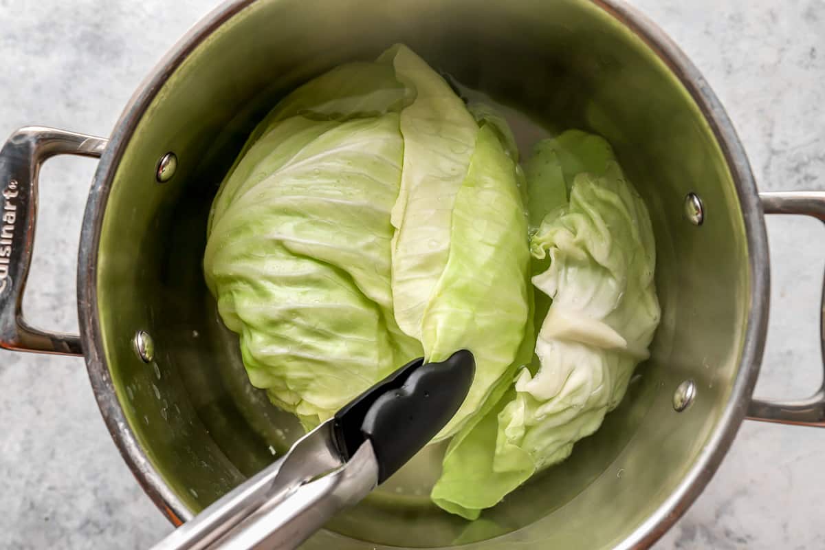 Cabbage in a pot with a pair of tongs.