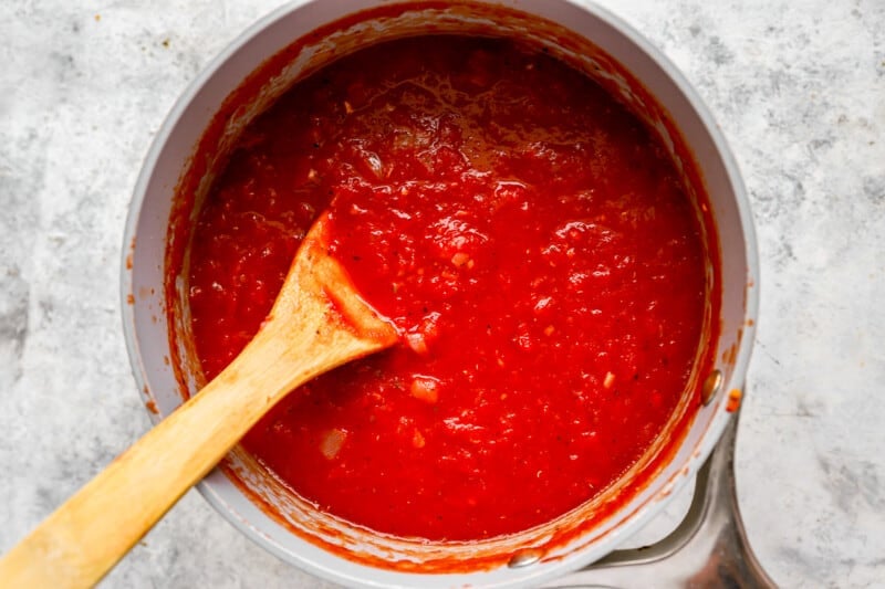 Tomato sauce in a pan with a wooden spoon.