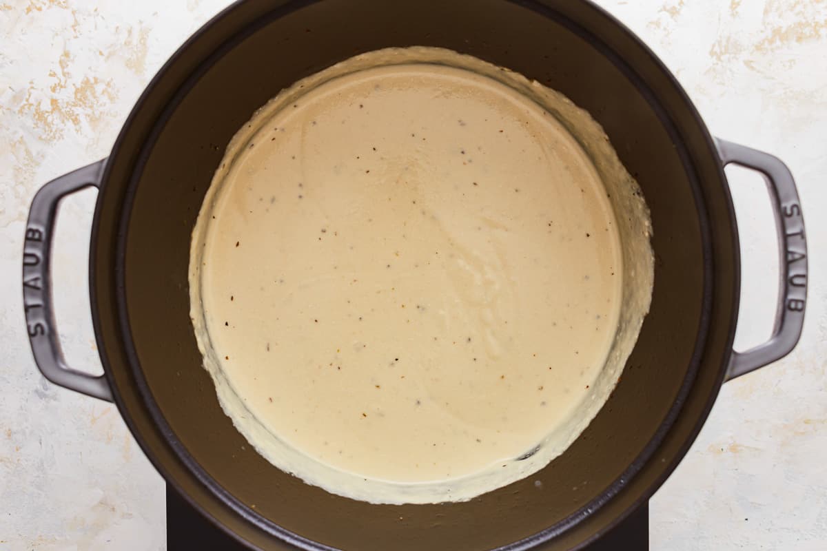 A slow cooker filled with a creamy sauce.