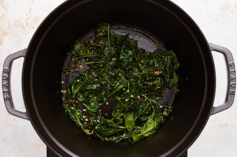 Spinach in a pan on a stove top.