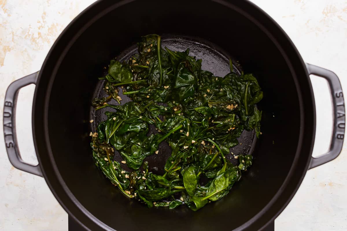 Spinach in a pan on a stove top.