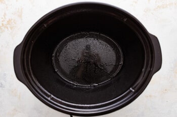 A black crock pot sitting on a white surface.
