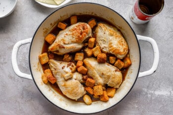 Chicken breasts in a pan with mashed potatoes and carrots.