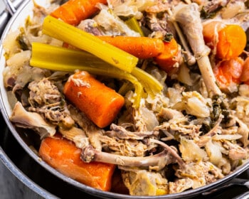 A pot with carrots, celery and chicken in it.