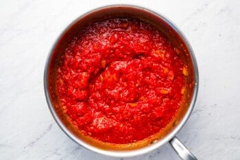 Red sauce in a pan on a marble countertop.