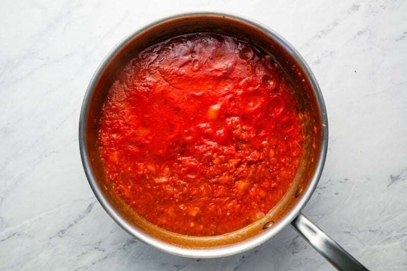 Tomato sauce in a pan on a marble countertop.