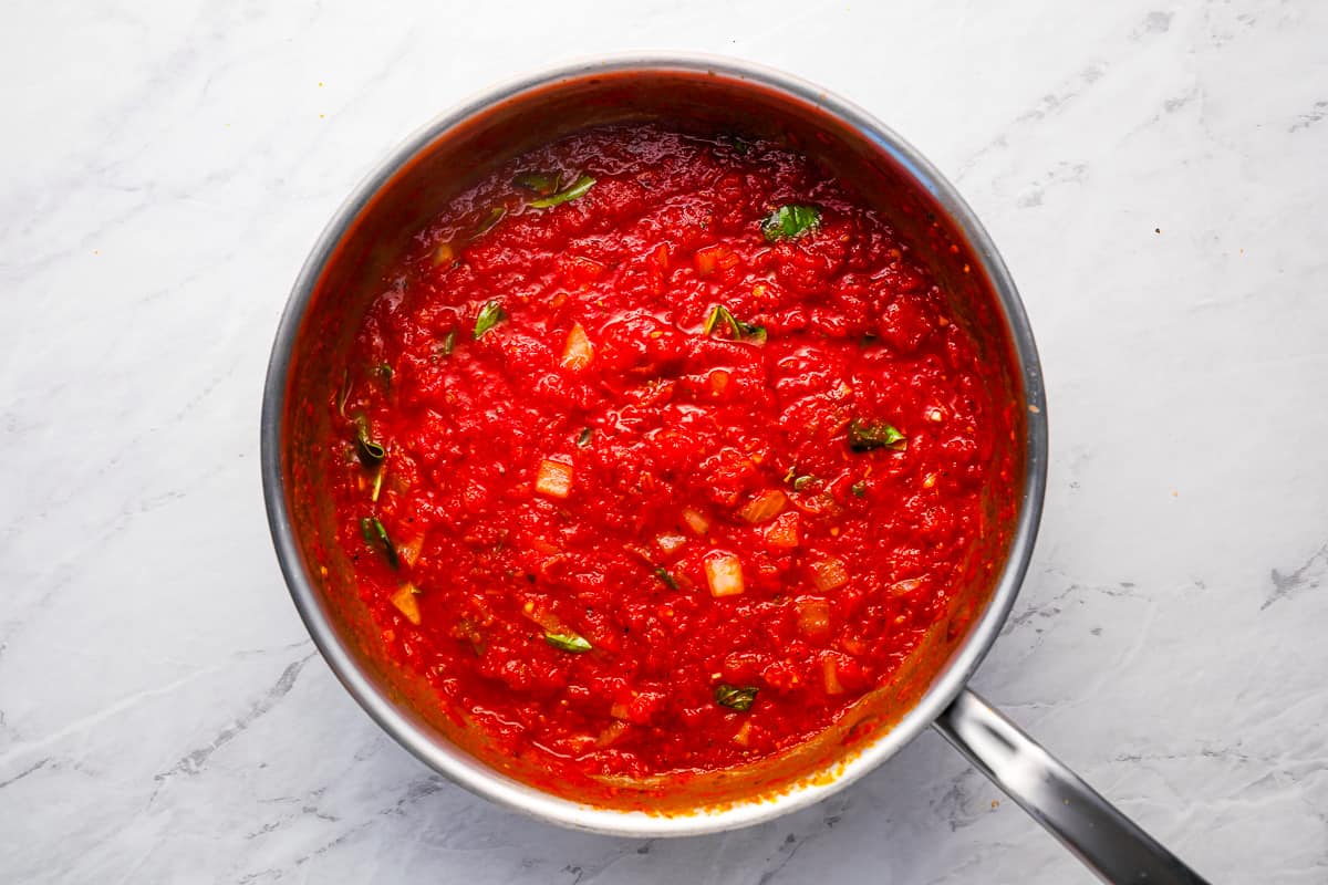 Tomato sauce in a pan on a marble countertop.