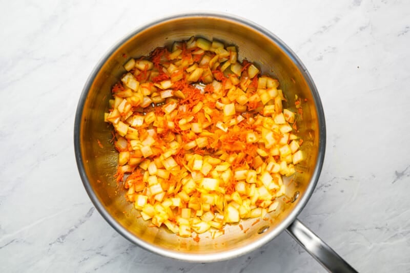 A frying pan filled with chopped carrots and onions.