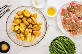 A plate of potatoes, green beans and steak on a white table.