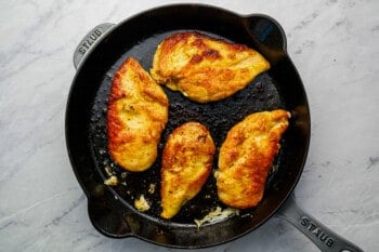 Fried chicken breasts in a cast iron skillet.