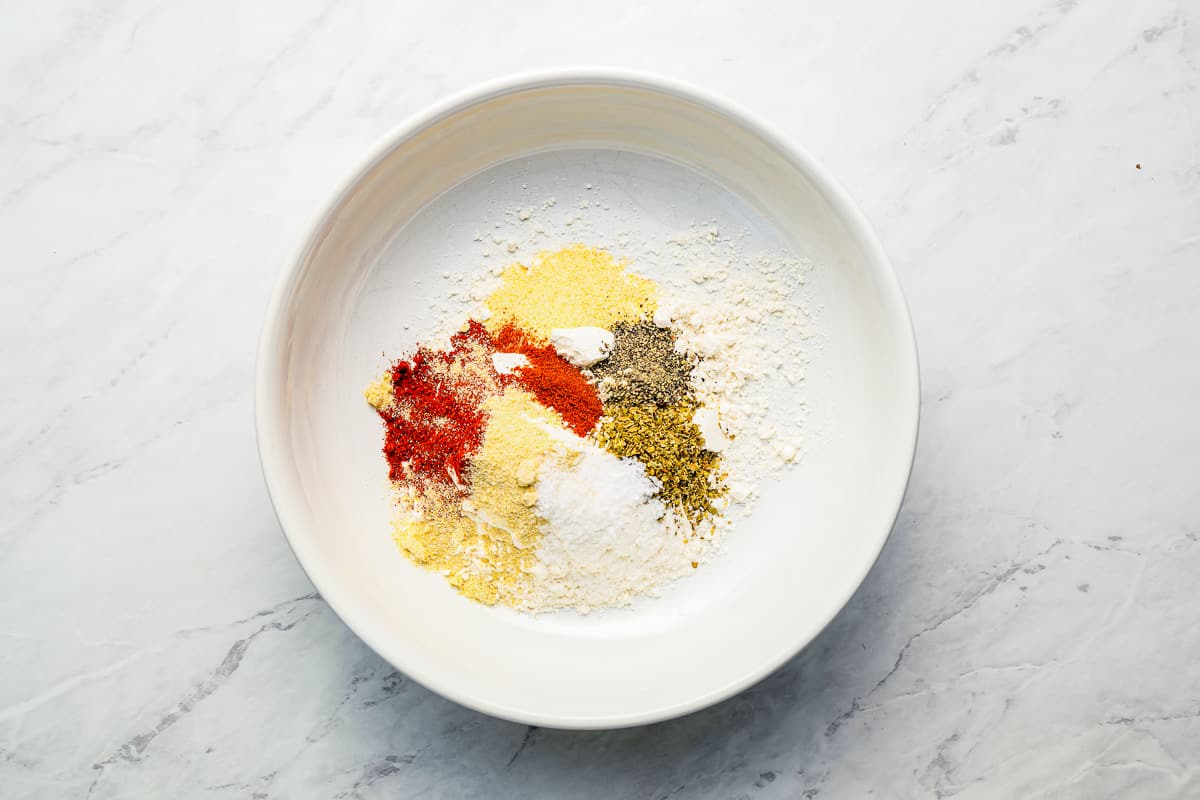 Spices in a white bowl on a marble table.