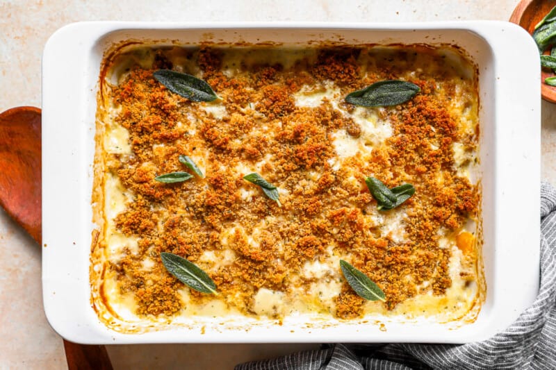 A casserole dish with sage sprigs on it.