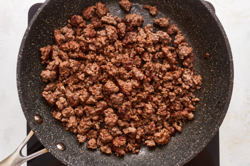 A frying pan with ground beef in it.