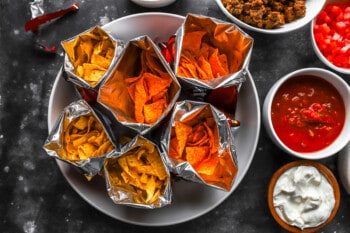 A plate of nachos, salsa, guacamole and sour cream.