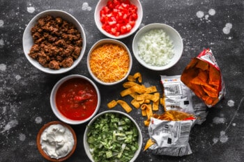 A bowl of tortilla chips, salsa, and sour cream.