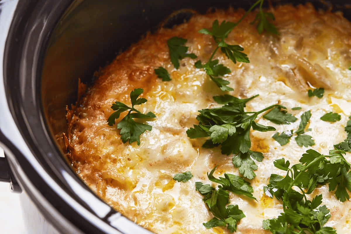 Cooked crockpot cheesy potatoes garnished with fresh parsley.