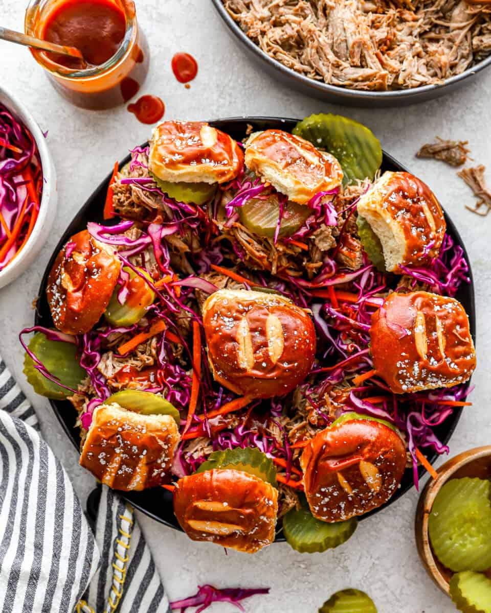 A plate of pulled pork sliders with coleslaw and pickles.