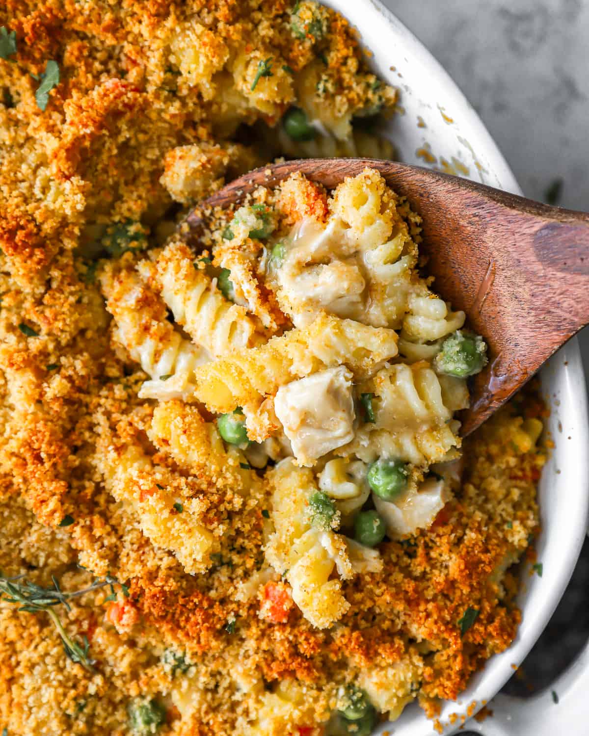 Leftover turkey casserole filled with peas, pasta, cubes of turkey, and breadcrumbs.