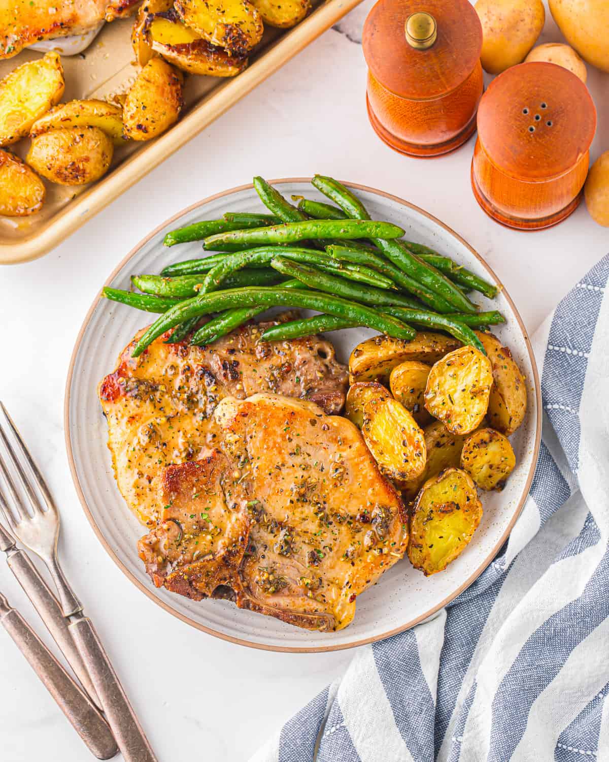 A plate of pork chops, green beans, and potatoes.