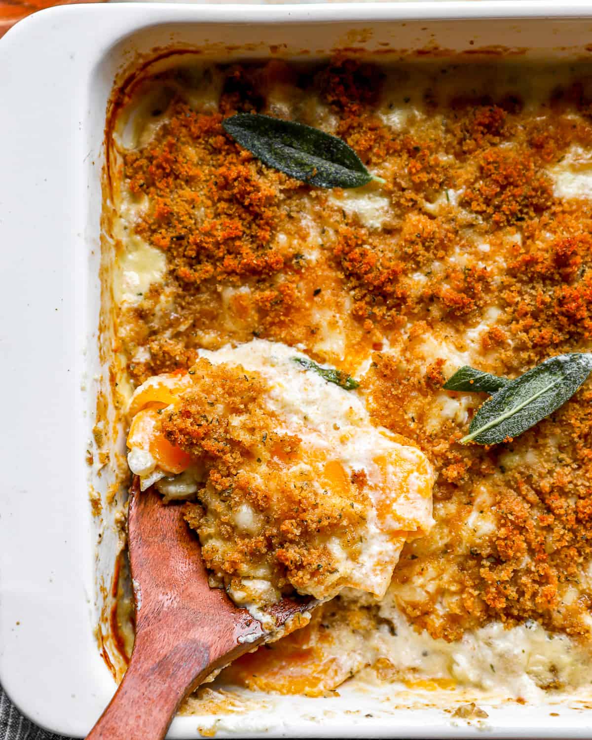 A butternut squash casserole dish with a wooden spoon in it.