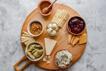 A wooden board with a variety of cheeses on it.