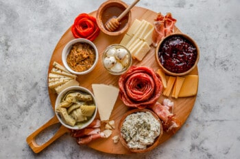 A wooden board with a variety of cheeses and meats on it.