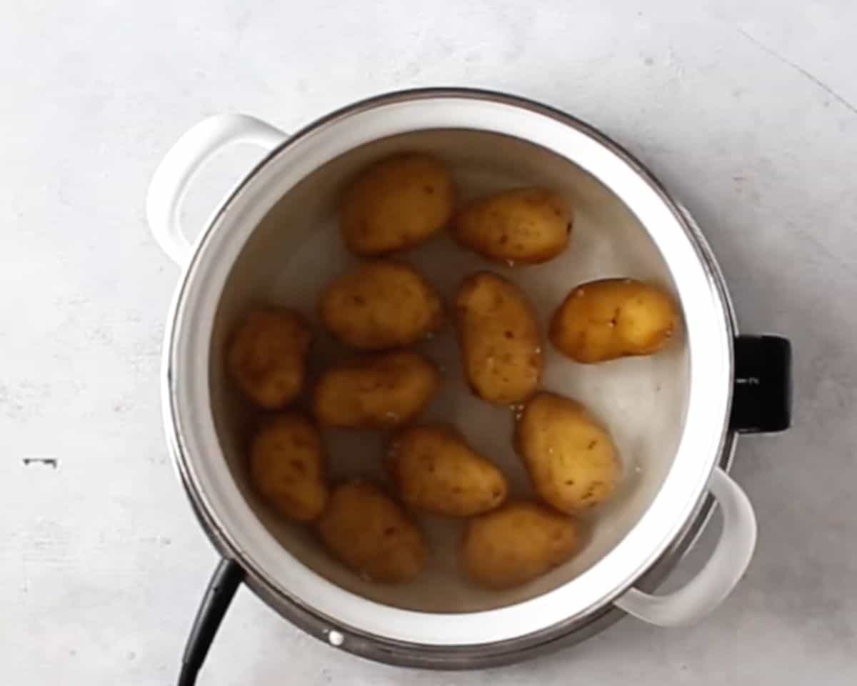 Baby Yukon Gold potatoes boiling in a pot of water until fork-tender before smashing. - 5