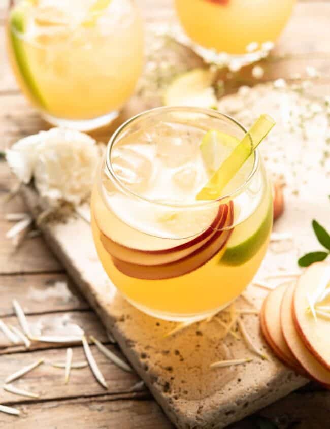 A refreshing apple pie drink garnished with slices of apples and sprigs of thyme.