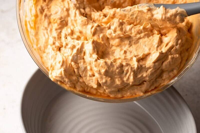 A bowl of mashed potatoes with a spoonful of buffalo chicken dip.