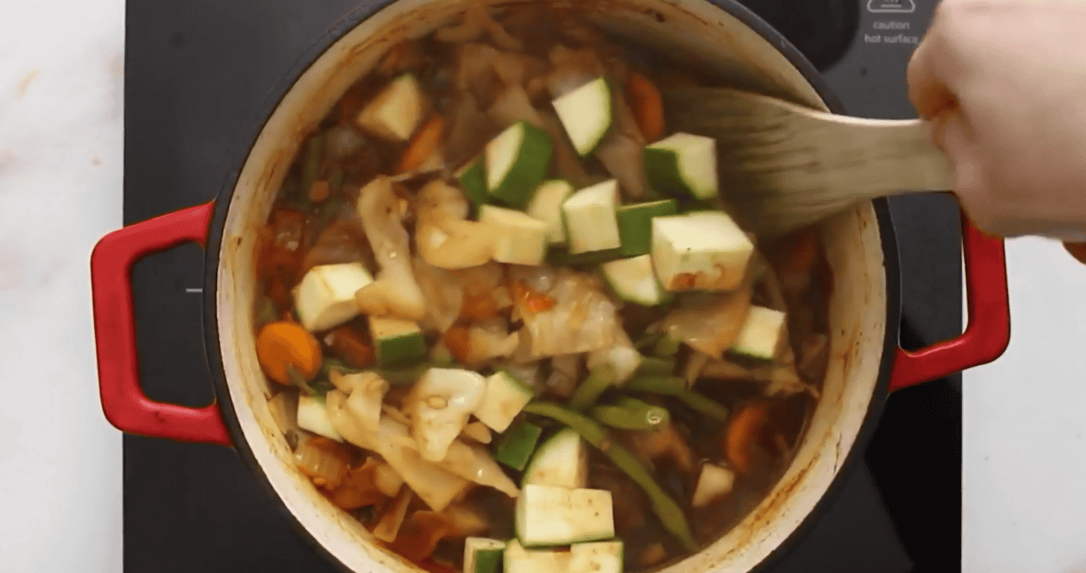 Adding zucchini to the soup pot. 