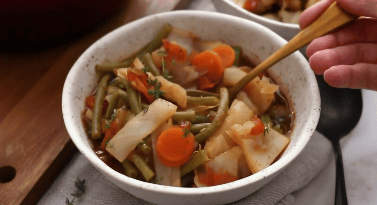 Cabbage soup in a white bowl with a spoon.