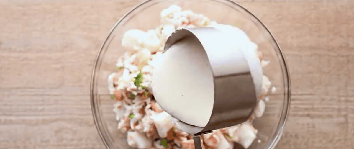 Pouring white sauce into the seafood mixture. 
