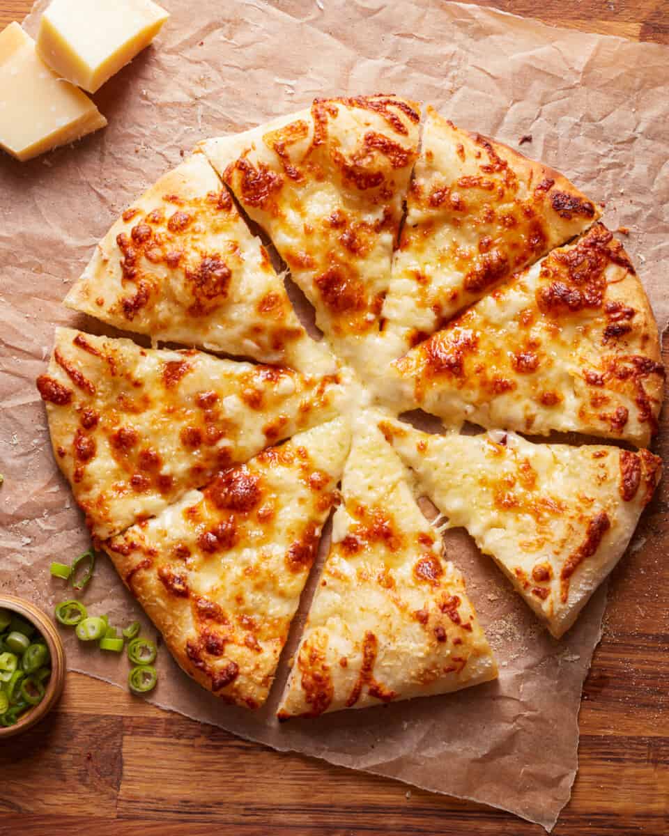 A whole pizza made with Alfredo sauce, and cut into slices.