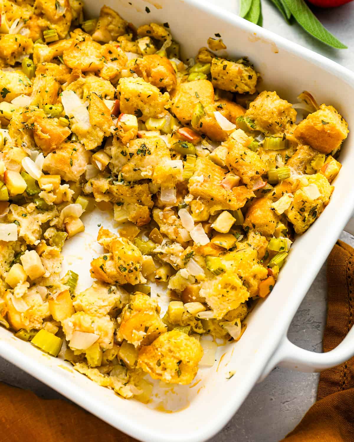 Herb and apple stuffing in a white baking dish.