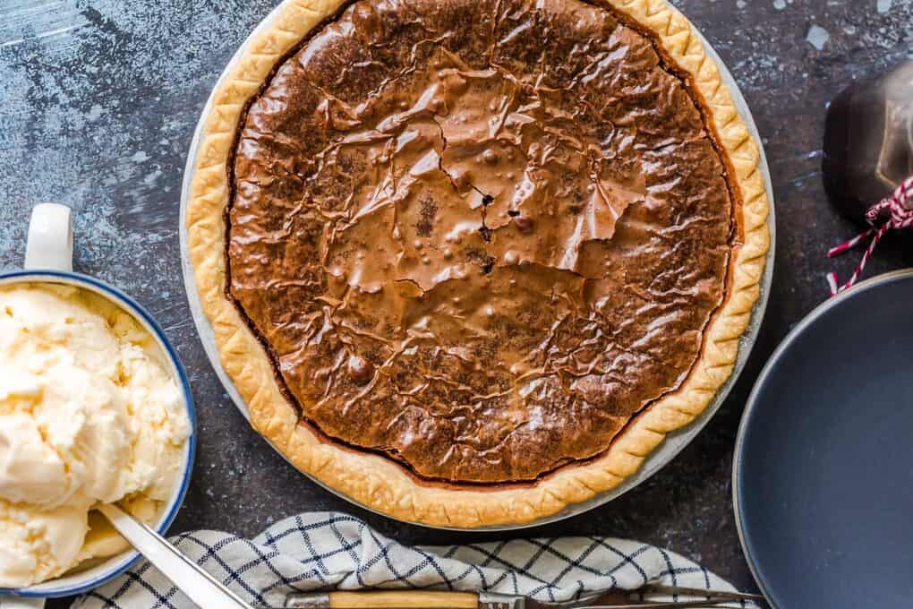 Overhead view of brownie pie in a pie pan next to a bowl of vanilla ice cream.