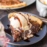 A slice of brownie pie topped with ice cream on a plate.