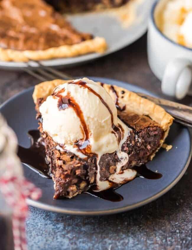 A slice of brownie pie topped with ice cream on a plate.