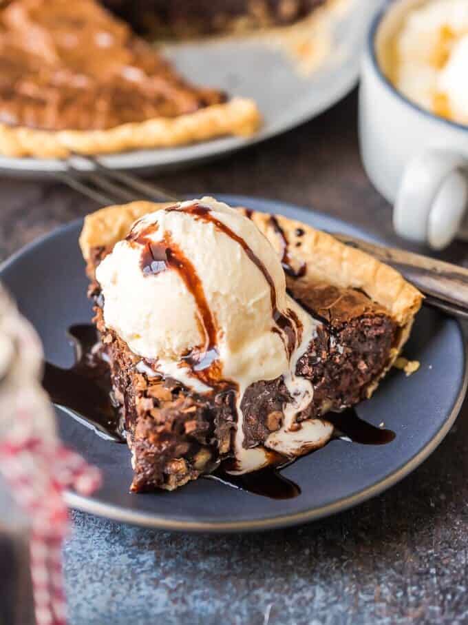 A slice of chocolate pie topped with vanilla ice cream and chocolate syrup on a blue plate.