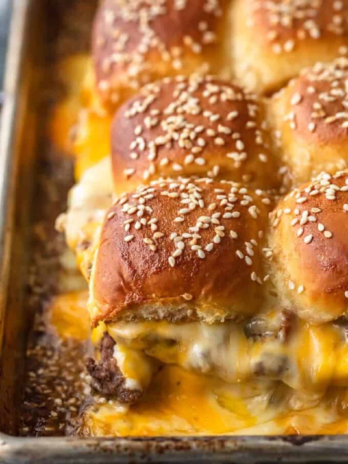 baked cheeseburger sliders with lots of melted cheese on sheet pan
