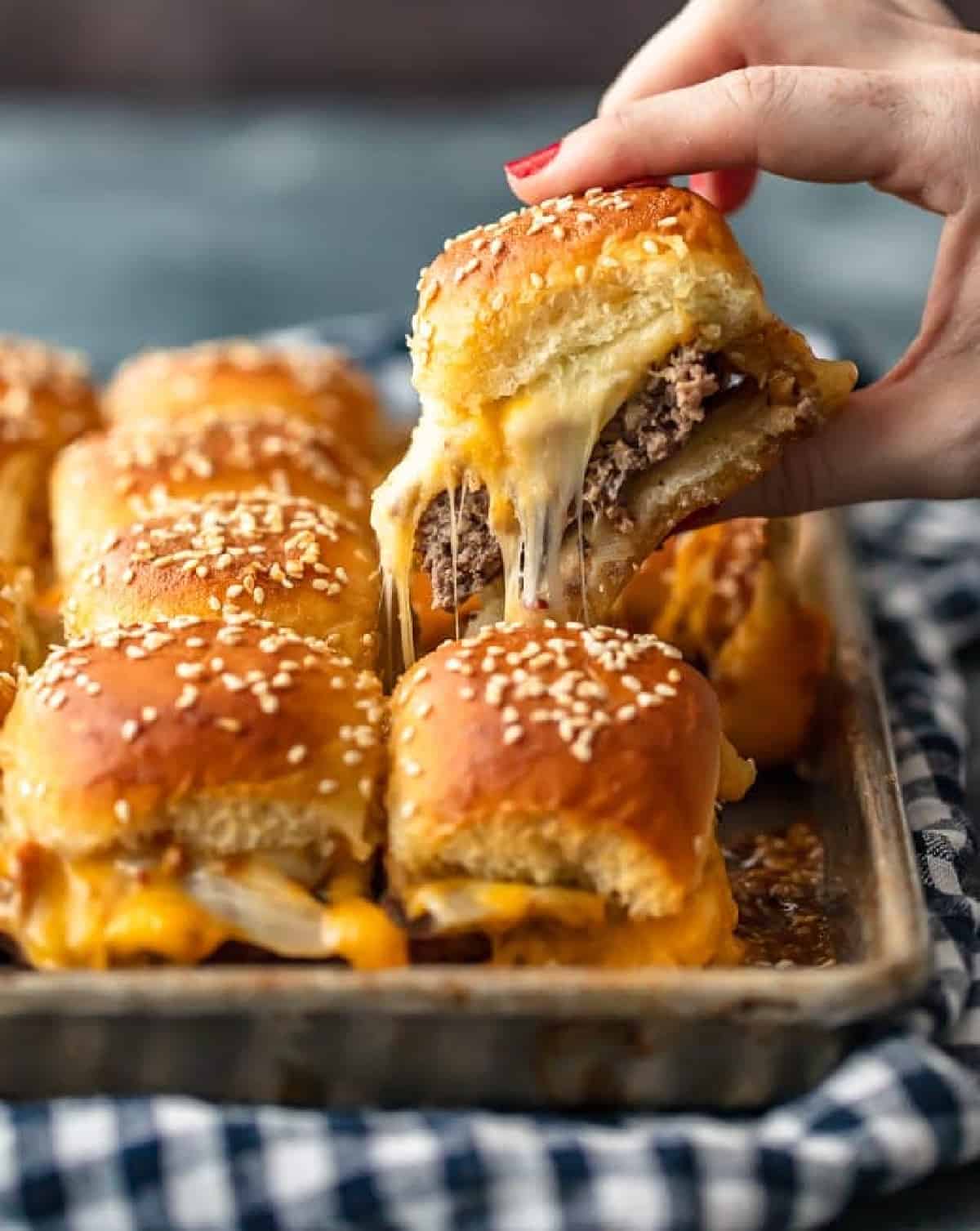 cheeseburger sliders on a pan with one lifting up