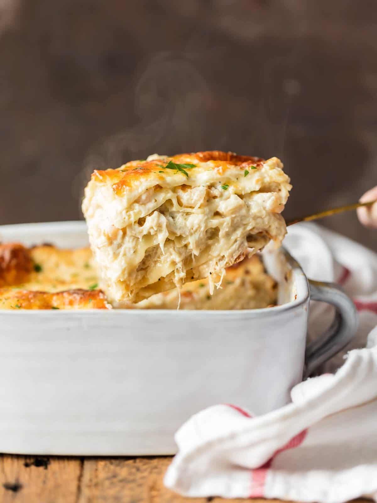 SEAFOOD LASAGNA is full of flavor, beautiful, and fool-proof. Layers of noodles, cheese, crab, shrimp, and more! This seafood lasagna recipe is so delicious! Cheesy Seafood Lasagna in a white baking pan
