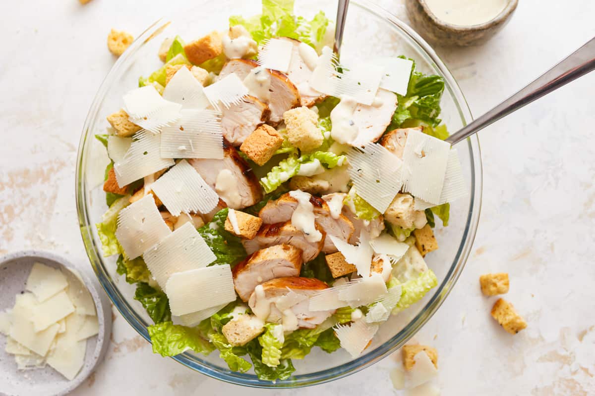 A bowl of chicken caesar salad with parmesan cheese and croutons.