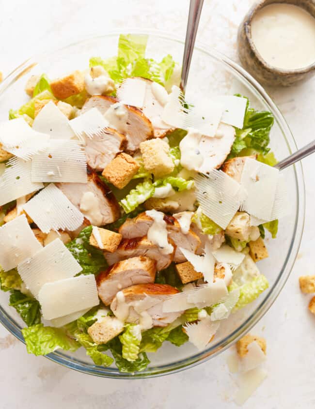 A bowl of chicken caesar salad with croutons and parmesan.