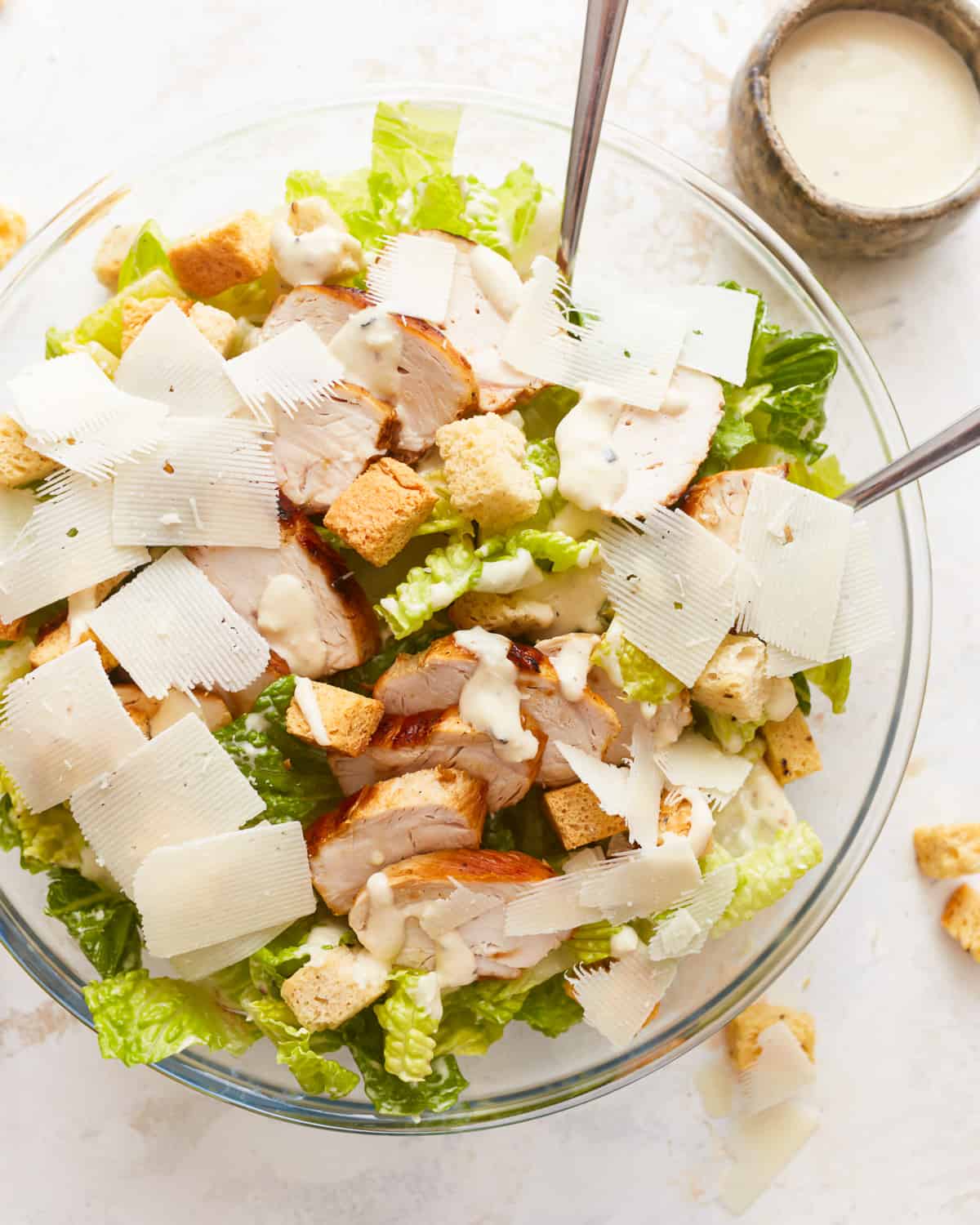 A bowl of chicken caesar salad with croutons and parmesan.